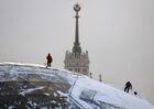 Utility workers remove snow from a pavilion roof at Zaryadye Park, with a Soviet era skyscraper on Kotelnicheskaya Embankment seen in the background, in central Moscow, Russia. Location: Russia, Moscow. Author: Alexey Maishev. Russia Weather