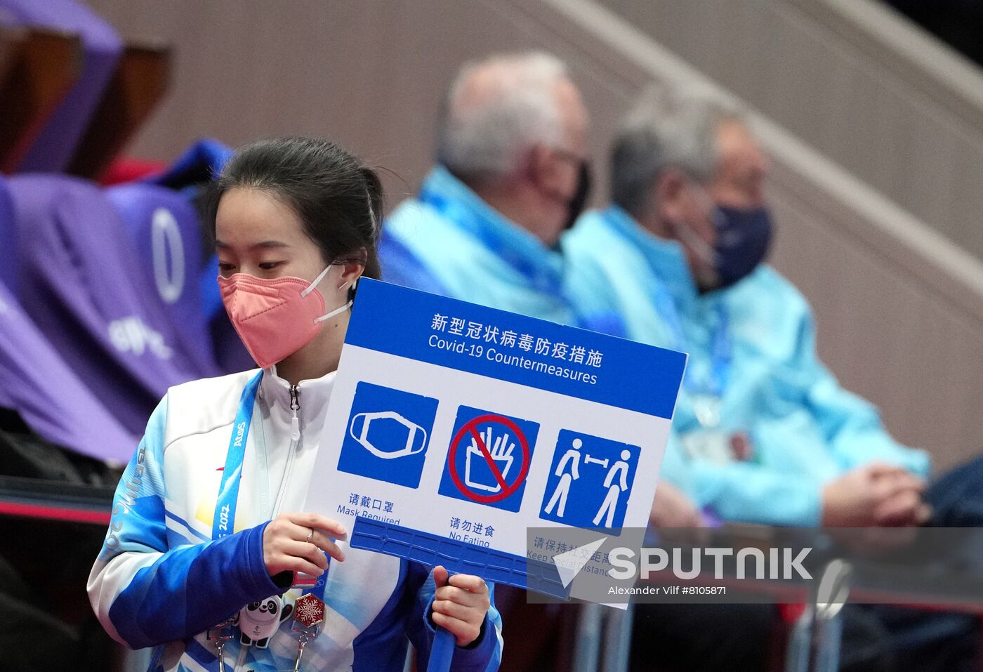 A volunteer carries a poster about COVID-19 countermeasures during the figure skating team event during the Beijing 2022 Winter Olympic Games at Capital Indoor Stadium in Beijing, China. Location: China, Beijing. Author: Alexander Vilf/Sputnik. China Olympics 2022 Figure Skating Team Event