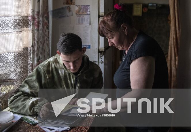 Luhansk resident Yuri Gluschenko and his mother Olga look at an album with family photos in their house in the village of Ganusovka, the Luhansk People's Republic. After the liberation of the village and that came under control of the Lugansk People's Republic, Yuri was able to meet with his mother, whom he had not seen for eight years. Location: Luhansk People's Republic. Author: Valery Melnikov/Sputnik. LPR Family Reunion