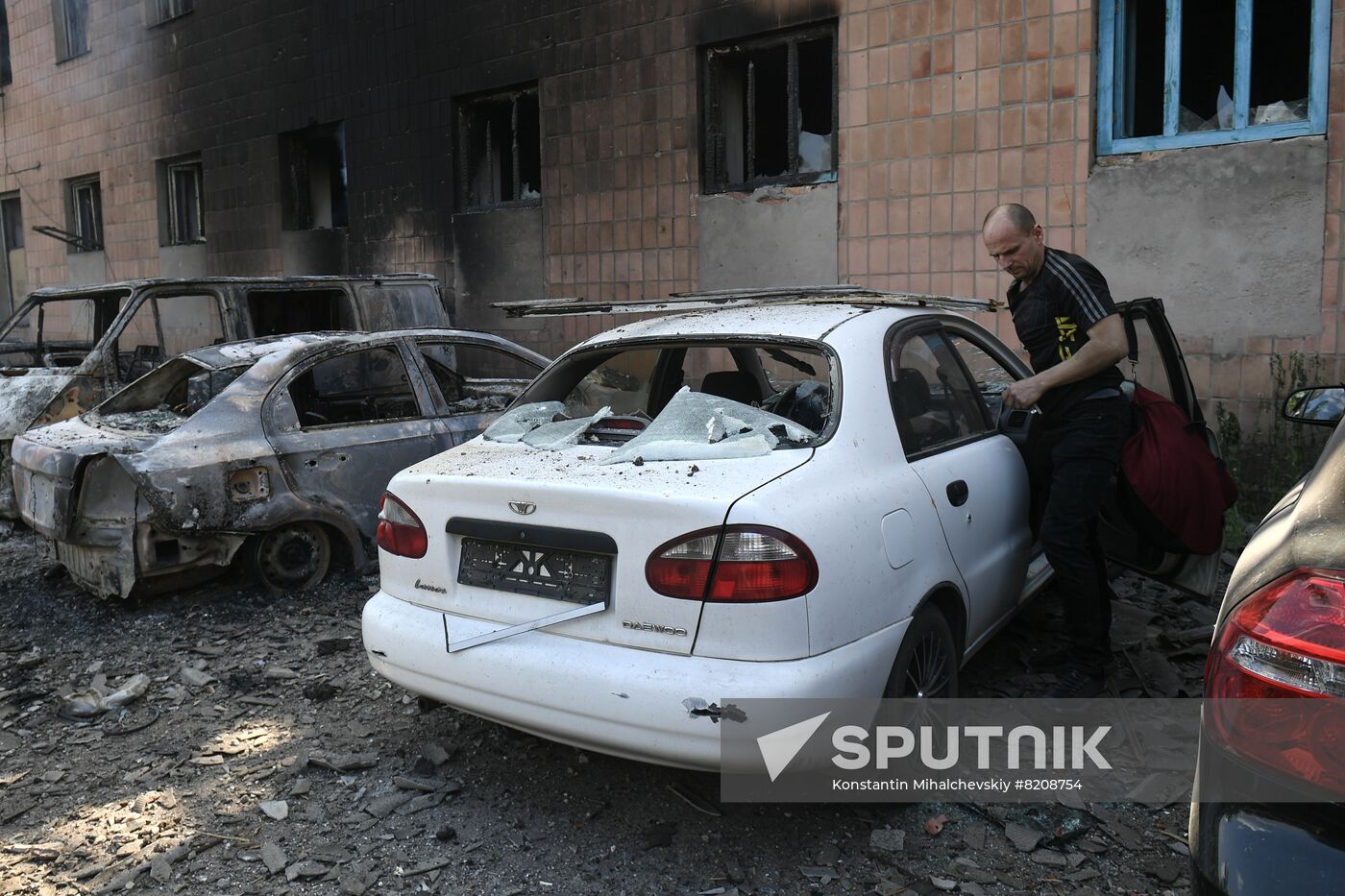 A man takes things out of his car damaged as a result of shelling are seen near the Chelyuskintsev mine in Donetsk, in the Donetsk People's Republic. Location: Donetsk People's Republic, Donetsk. Author: Konstantin Mihalchevskiy/Sputnik. DPR Russia Ukraine Military Operation Shelling