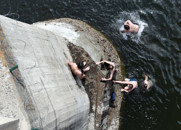 Teenagers dive into the Mana River from a concrete bridge post during a hot summer day in the East Siberian taiga, Krasnoyarsky Krai region, Russia. Russia Weather
