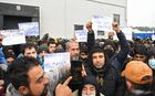 Refugees hold placards at the Bruzgi logistics centre providing accommodation to migrants near the Bruzgi-Kuznica Bialostocka border crossing at the Belarusian-Polish border in Grodno region, Belarus. Migrants from the Middle East and North Africa trapped in Belarus have converged on the border with Poland, where razor wire fences and Polish troops have repeatedly blocked their entry. Location: Belarus, Grodno Region. Author: Pavel Bednyakov/Sputnik. Belarus Poland Border Refugees