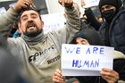 Refugees hold placards at the Bruzgi logistics centre providing accommodation to migrants near the Bruzgi-Kuznica Bialostocka border crossing at the Belarusian-Polish border in Grodno region, Belarus. Migrants from the Middle East and North Africa trapped in Belarus have converged on the border with Poland, where razor wire fences and Polish troops have repeatedly blocked their entry. Location: Belarus, Grodno Region. Author: Pavel Bednyakov/Sputnik. Belarus Poland Border Refugees