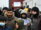Refugees hold placards at the Bruzgi logistics centre providing accommodation to migrants near the Bruzgi-Kuznica Bialostocka border crossing at the Belarusian-Polish border in Grodno region, Belarus. Migrants from the Middle East and North Africa trapped in Belarus have converged on the border with Poland, where razor wire fences and Polish troops have repeatedly blocked their entry. Location: Belarus, Grodno Region. Author: Pavel Bednyakov/Sputnik. Belarus Poland Border Refugees