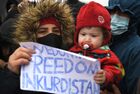 A refugee with a child holds a placard reading "we don't have freedom in Kurdistan" at the Bruzgi logistics centre providing accommodation to migrants near the Bruzgi-Kuznica Bialostocka border crossing at the Belarusian-Polish border in Grodno region, Belarus. Migrants from the Middle East and North Africa trapped in Belarus have converged on the border with Poland, where razor wire fences and Polish troops have repeatedly blocked their entry. Location: Belarus, Grodno Region. Author: Pavel Bednyakov/Sputnik. Belarus Poland Border Refugees