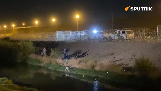 Migrants gather outside the bollard fencing on the US-Mexico border