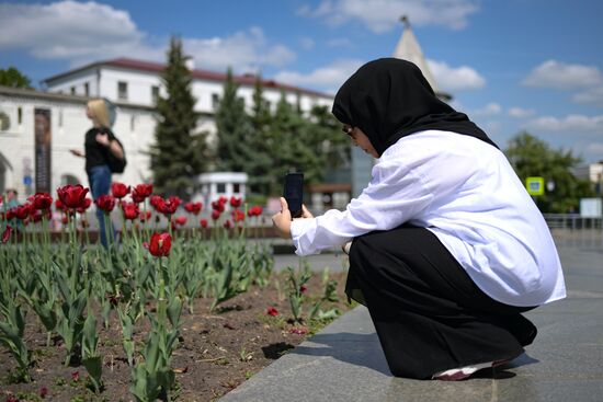 A forum participant is seen taking photos of tulips near the Kazan Kremlin State Historical, Architectural and Artistic Reserve Museum during a sightseeing tour of the city. Photos may be used as stated in the media bank section concerning the forum. Location: Russia, Republic of Tatarstan, Kazan. Author: Alexandr Kryazhev/ANO “Directorate for Sports and Social Projects”. KAZANFORUM 2023. Sightseeing tour of Kazan